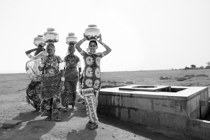 Nature-based solution for quenching thirst in the driest place of India - Returning  home with pots full of drinking water from a 'beri'  (shallow well) in the dry bed of Viprasar, a rainfed pond in Thar Desert, Jaisalmer district, Rajasthan